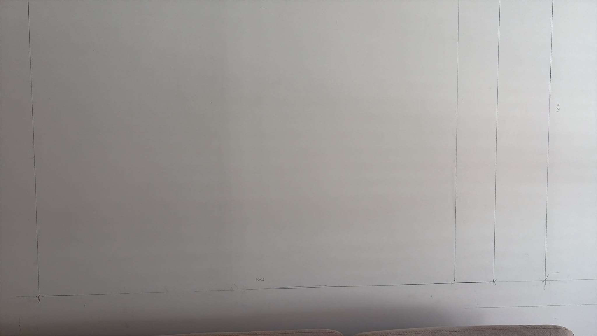 Pencil markings on a white wall showing the layout for a custom carpentry installation, with measurements visible.