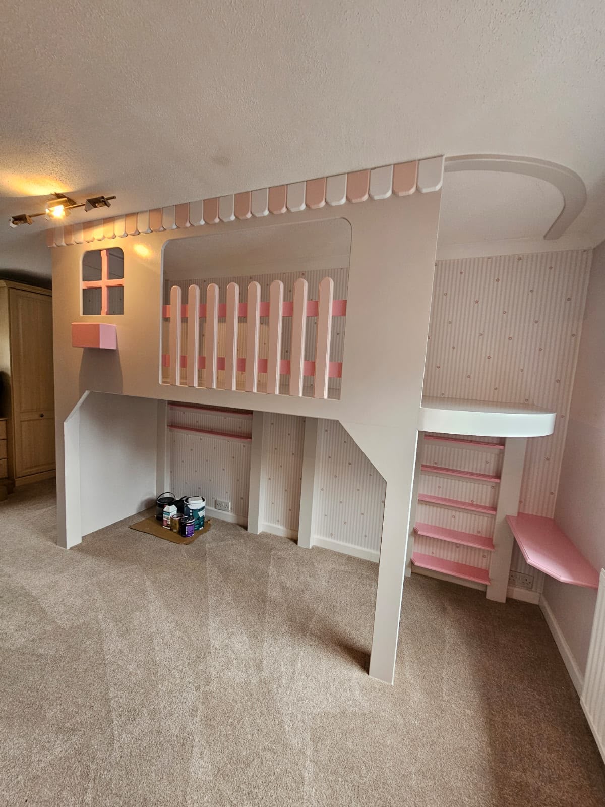 Kids' bedroom makeover: bespoke pink and white playhouse loft bed with a desk, shelves and steps underneath