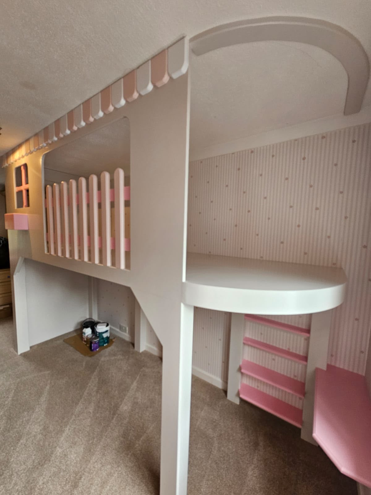 Custom loft bed with pink and white accents in a children's room.